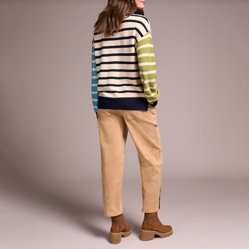 Person wearing a striped sweater and beige pants on a plain background