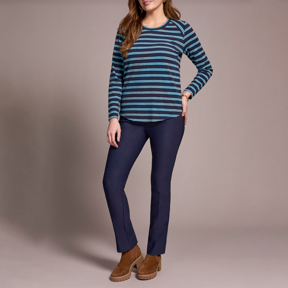 Woman wearing a blue and green striped sweater and navy pants on a beige background