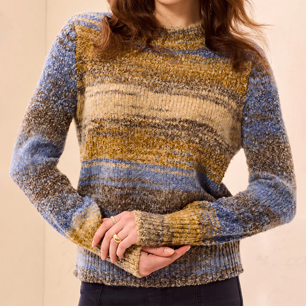 A woman wearing a marled knit sweater with horizontal stripes in blue, beige, and brown tones, cropped from the chin down against a plain beige background.