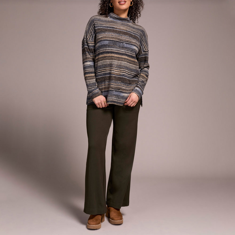 Person wearing a striped sweater and dark pants against a plain background