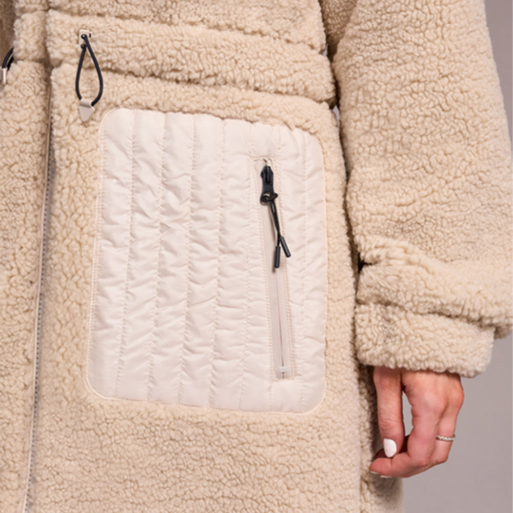 Close-up of a beige fleece jacket with a pocket and zipper detail.