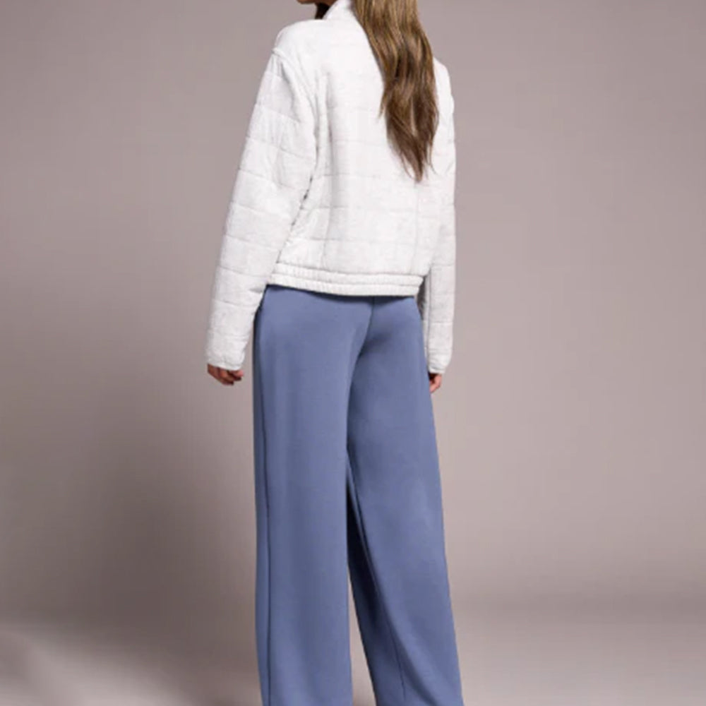 Person wearing a white puffer jacket and blue pants on a plain background