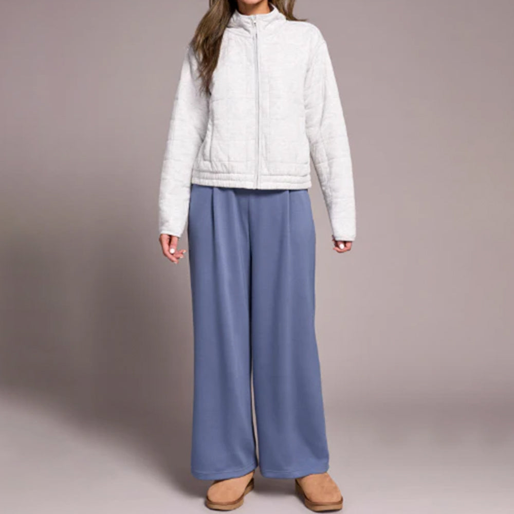 Person wearing a white jacket and blue pants on a plain background