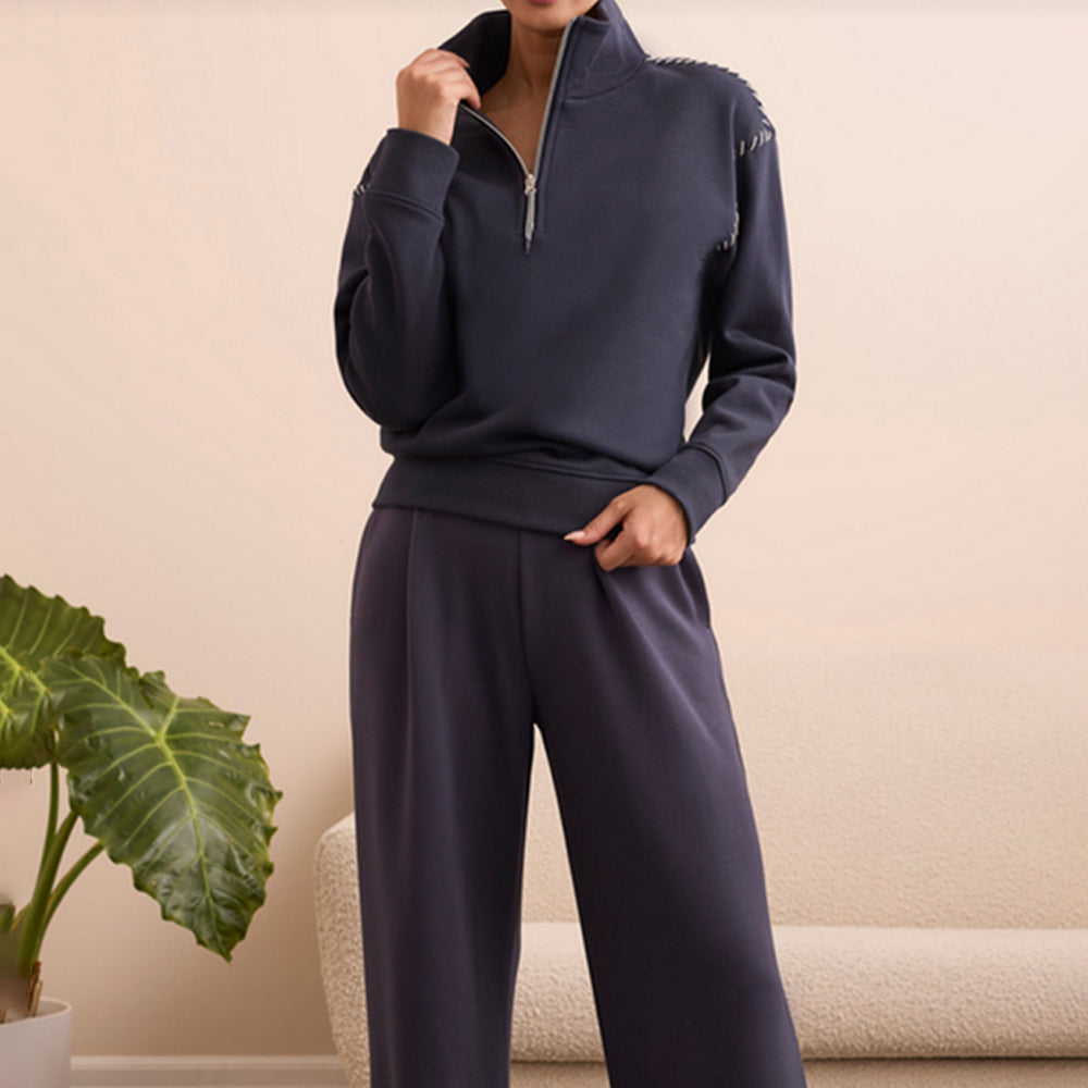 Woman wearing a blue quarter zip pullover whit stitching around the shoulders