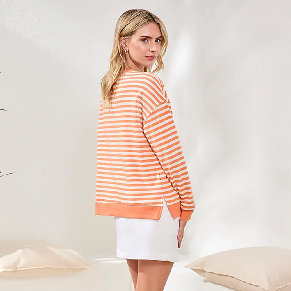 Woman wearing an orange and white striped sweater in a minimalistic setting