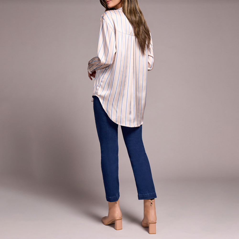 Woman wearing a striped shirt and blue jeans on a plain background