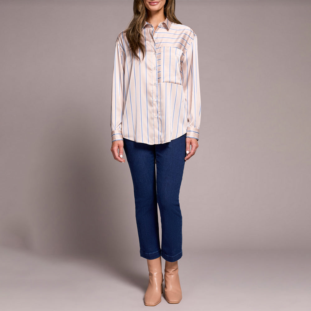 Woman wearing a striped shirt and blue jeans against a plain background