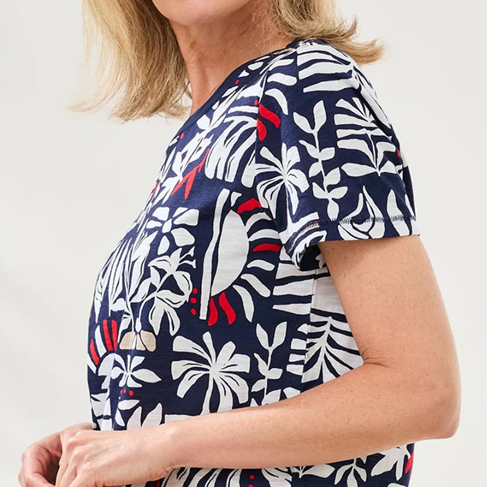 Woman wearing a navy blue scrub top with white floral pattern