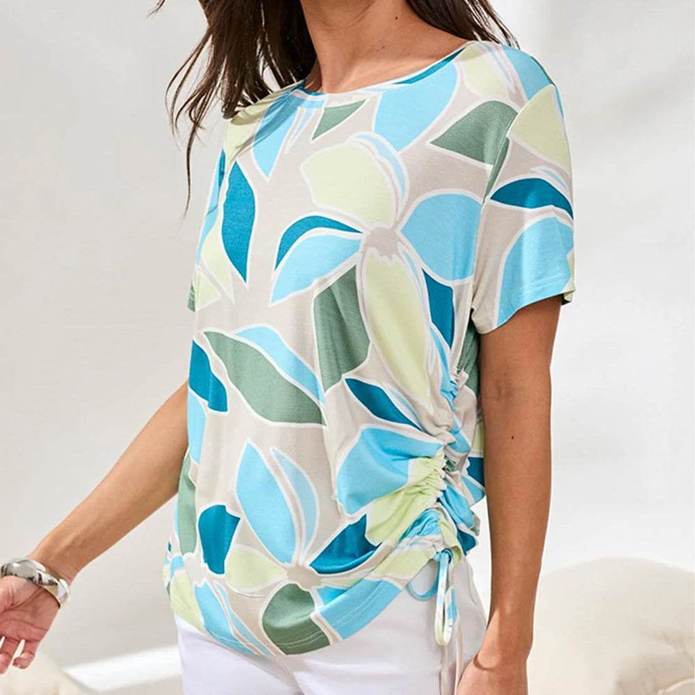 Woman wearing a colorful floral-patterned top against a white background
