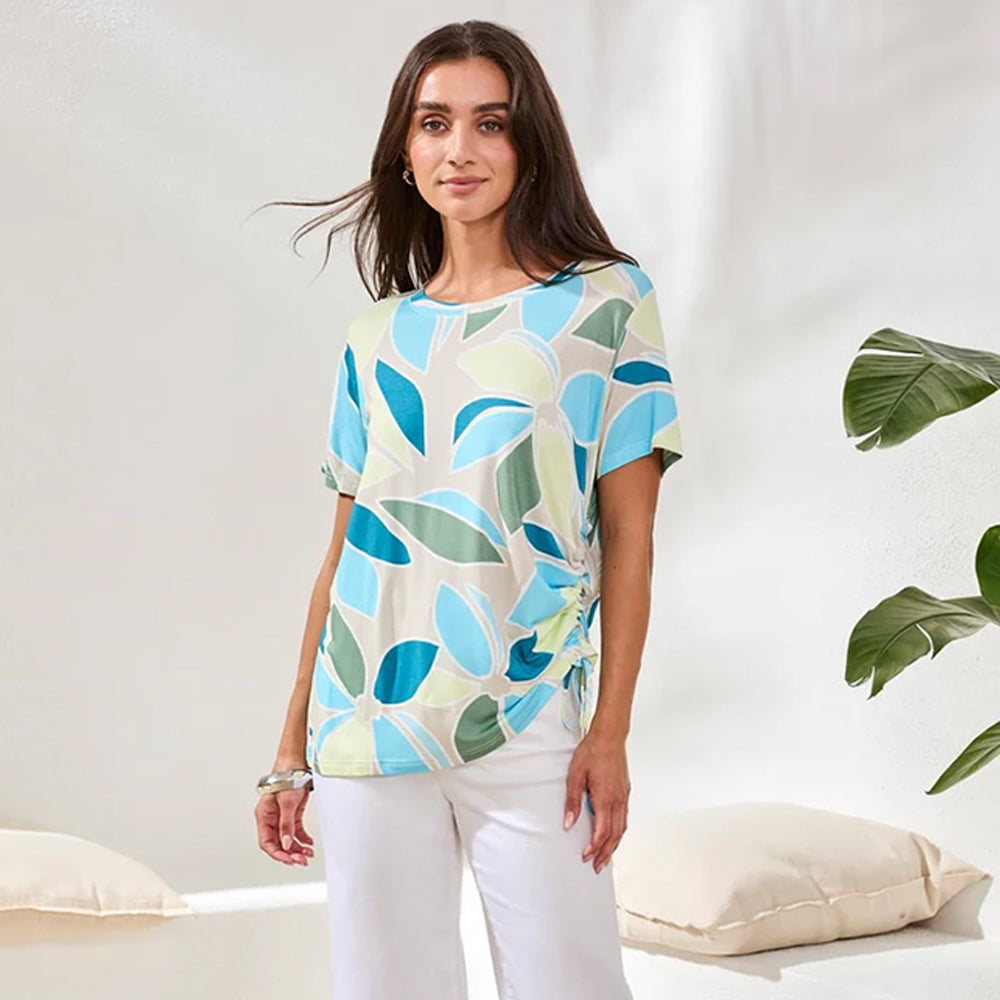 Woman wearing a colorful leaf-patterned shirt in a minimalistic setting