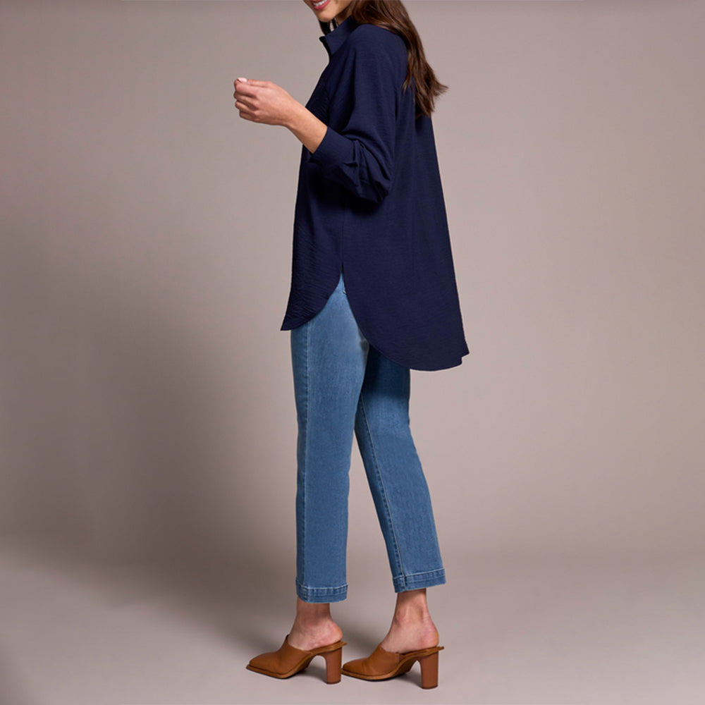 Person wearing a navy blue top and blue jeans on a beige background