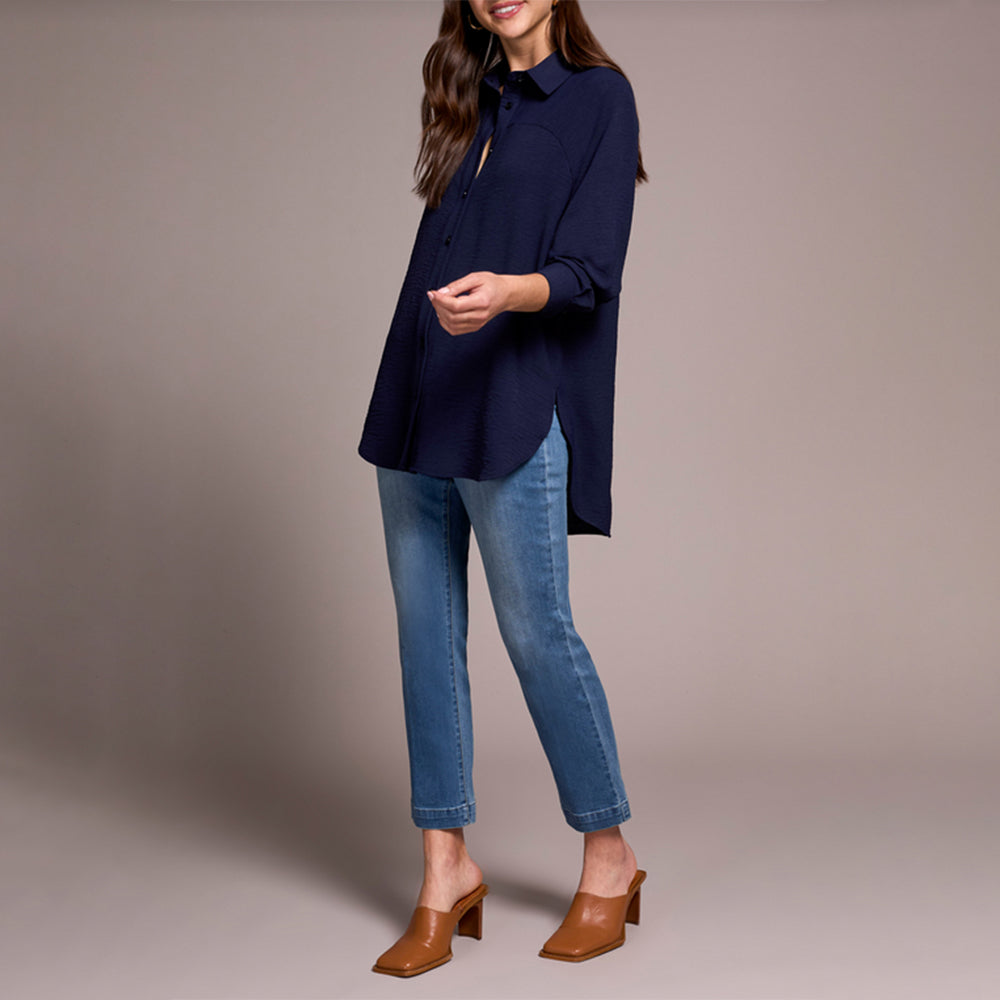 Person wearing a navy blue top and blue jeans on a beige background