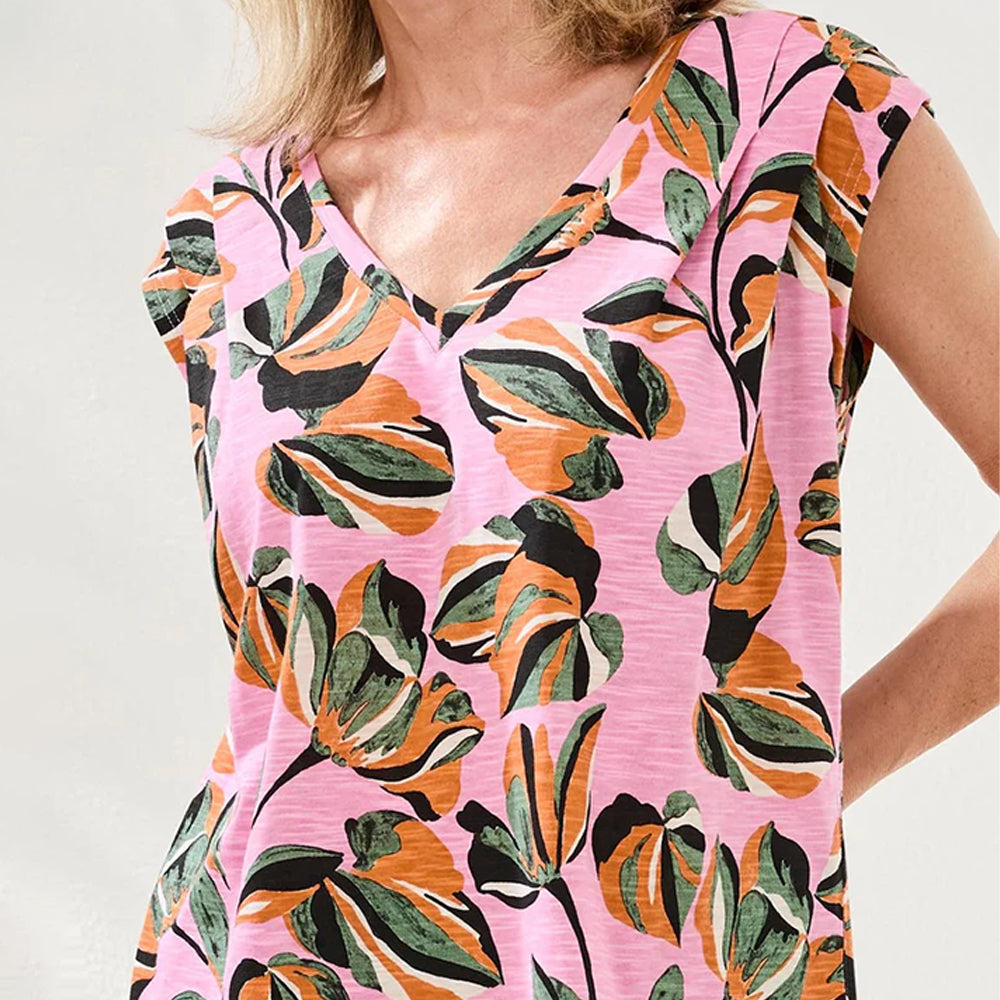 Woman wearing a pink dress with colorful floral pattern on a plain background