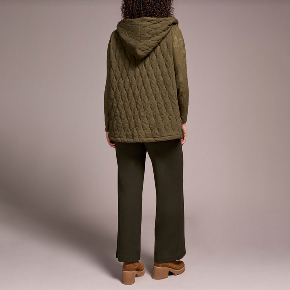 Woman wearing green zipper vest with brown pants and brown boots.