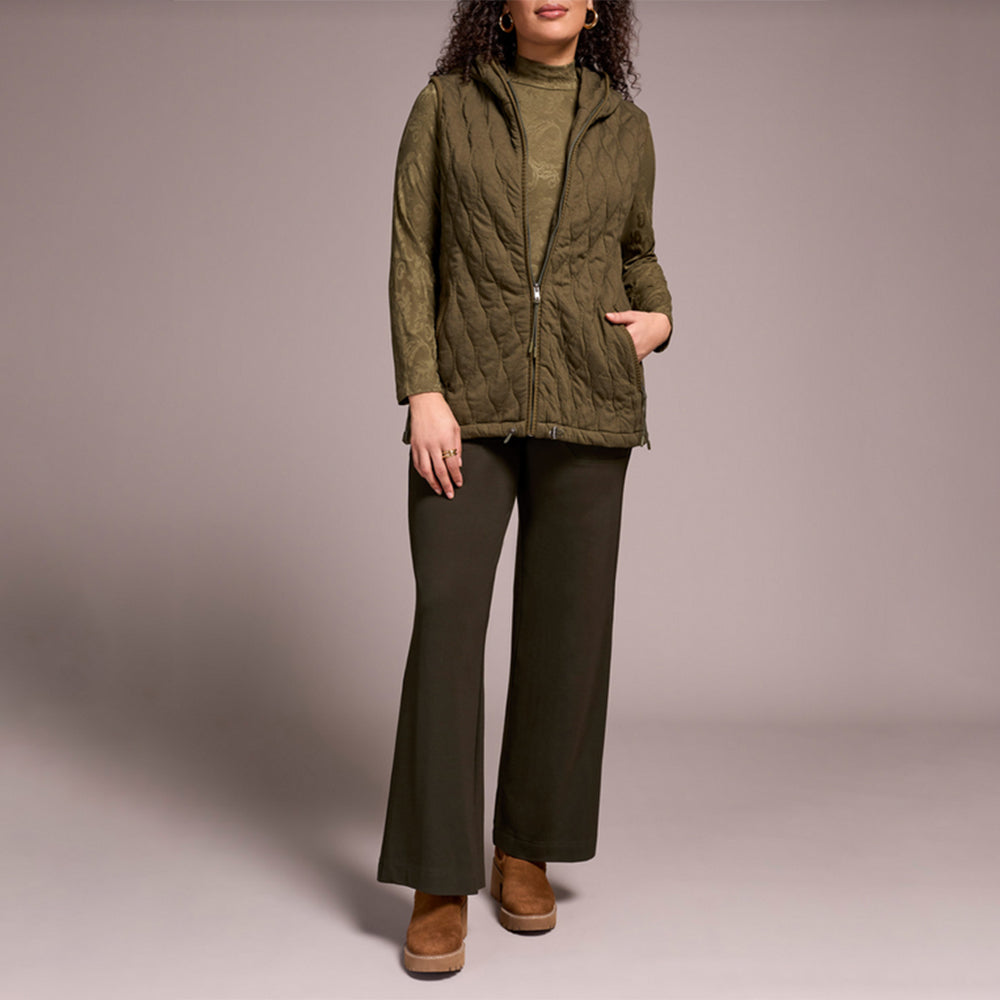 Woman wearing green zipper vest with brown pants and brown boots.