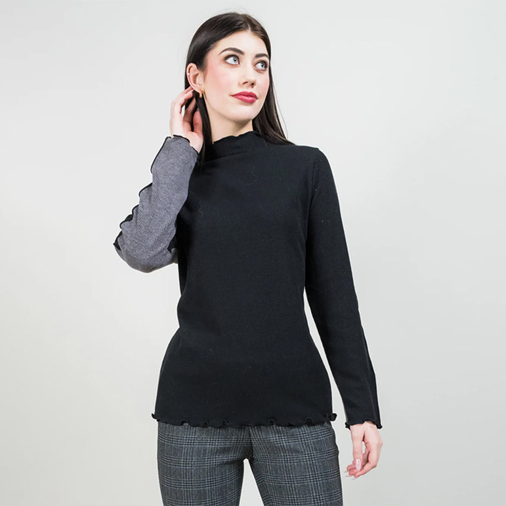 Woman wearing a black turtleneck sweater with gray sleeves on a light gray background