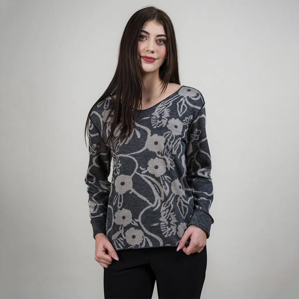 Woman wearing a floral patterned sweater against a plain background