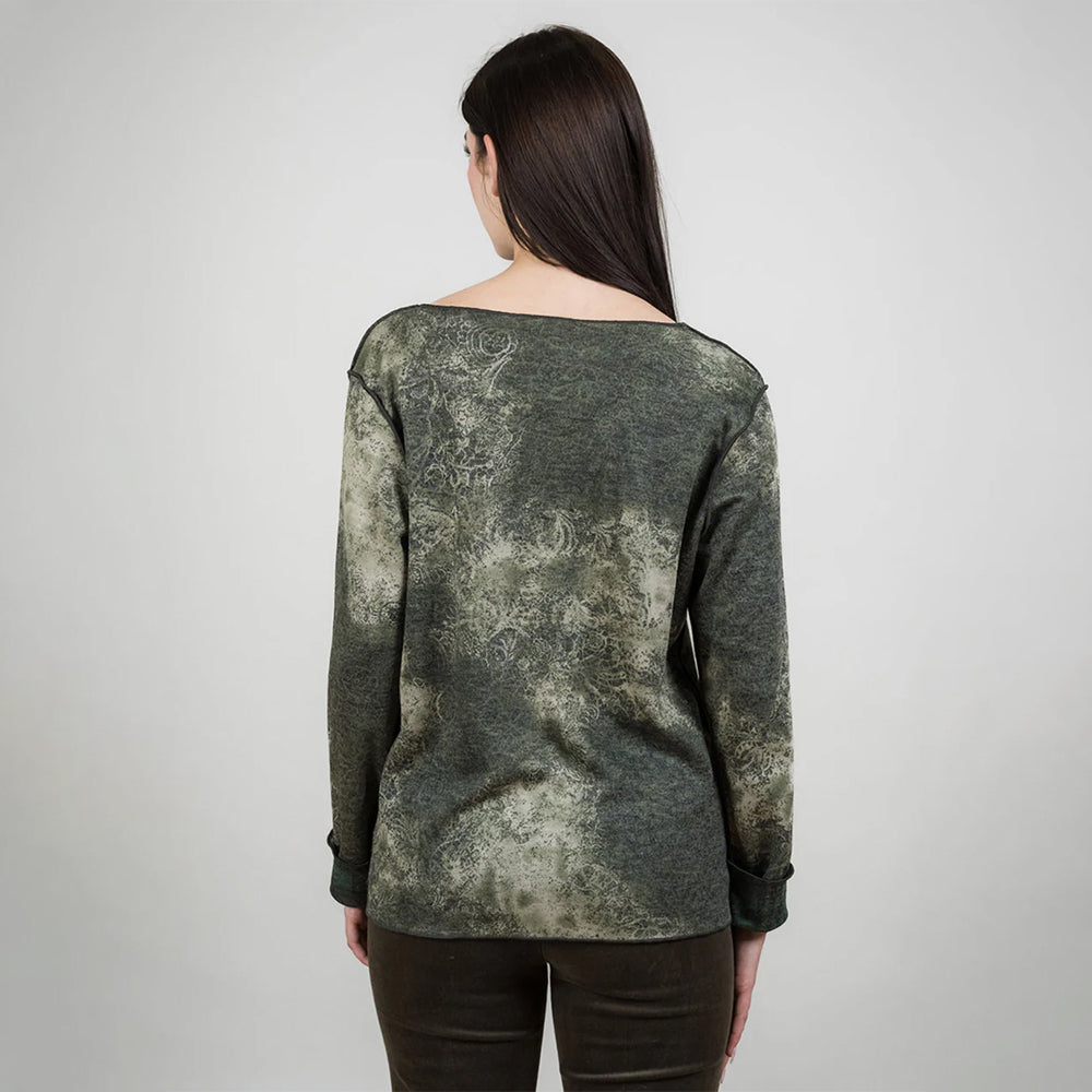 Woman wearing a green patterned top against a white background