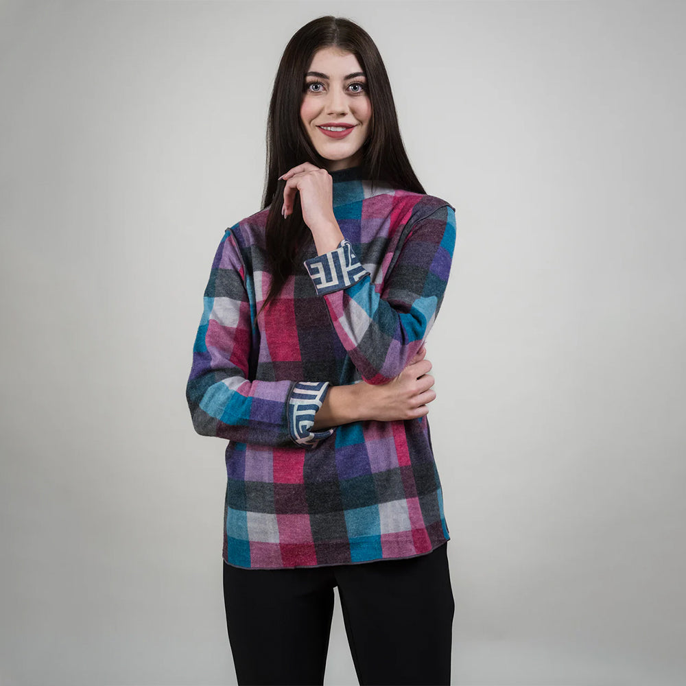 Woman wearing a colorful plaid sweater on a gray background