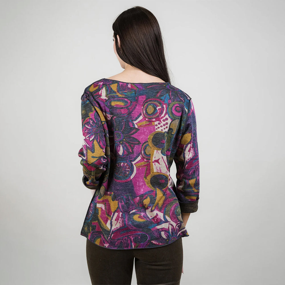 Woman wearing a colorful patterned top on a plain background