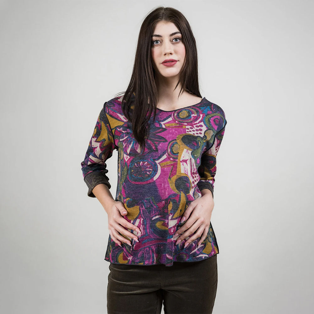 Woman wearing a colorful patterned top against a plain background