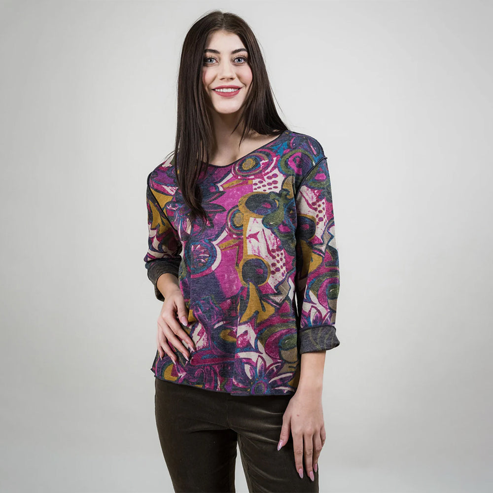 Woman wearing a colorful patterned top against a plain background
