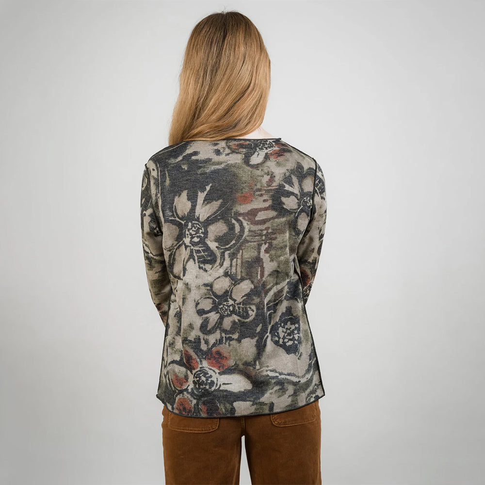 Person wearing a floral patterned top with long sleeves on a plain background