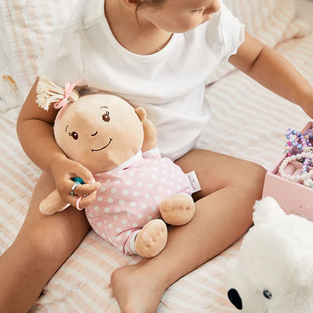 Child holding a plush toy with a smiling face on a soft surface