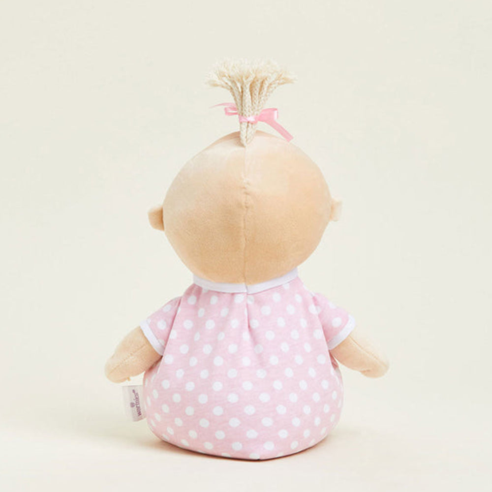 Stuffed doll with a pink polka dot dress on a beige background