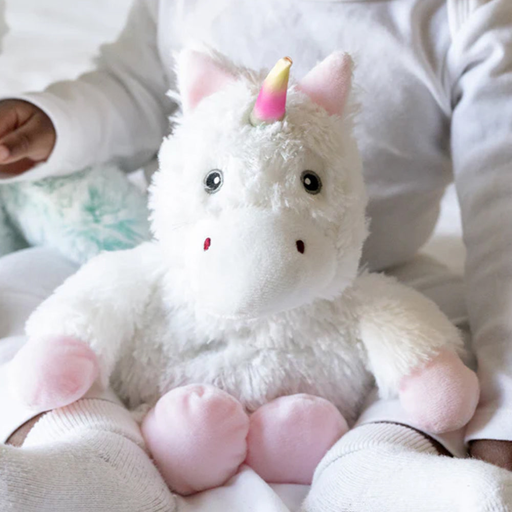 Plush unicorn toy held by a person wearing a white sweater.