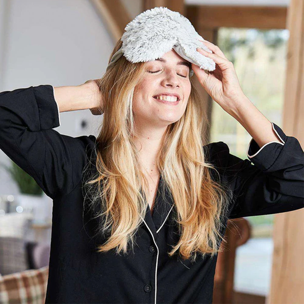 Woman wearing a fluffy white sleep mask indoors