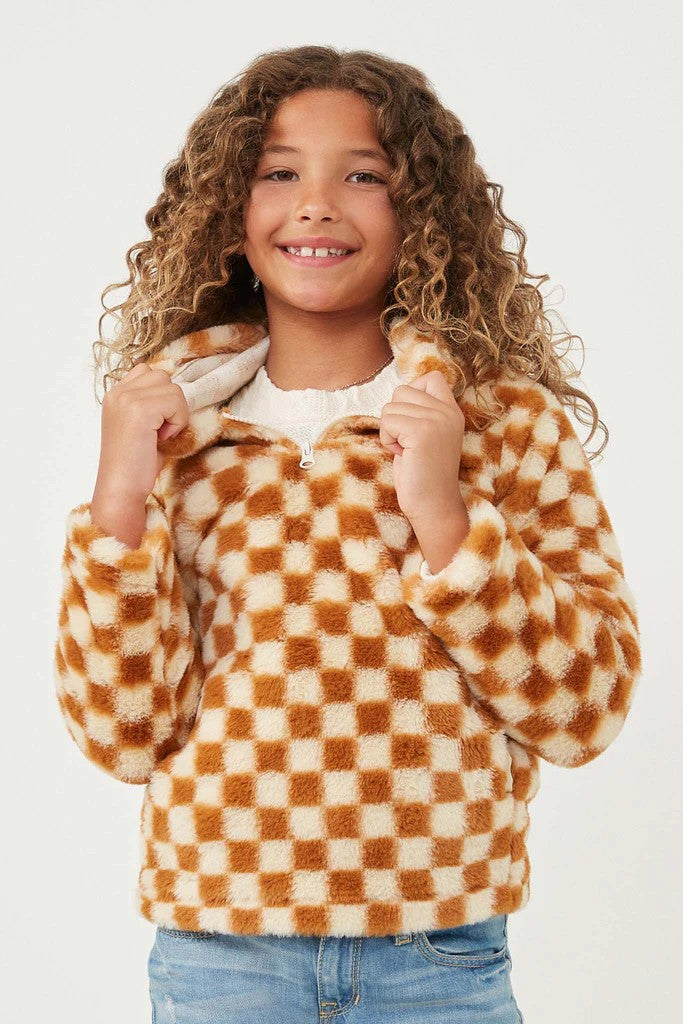 Young girl with curly hair wearing a rust colored checkered fleece hoodie and blue jeans.  