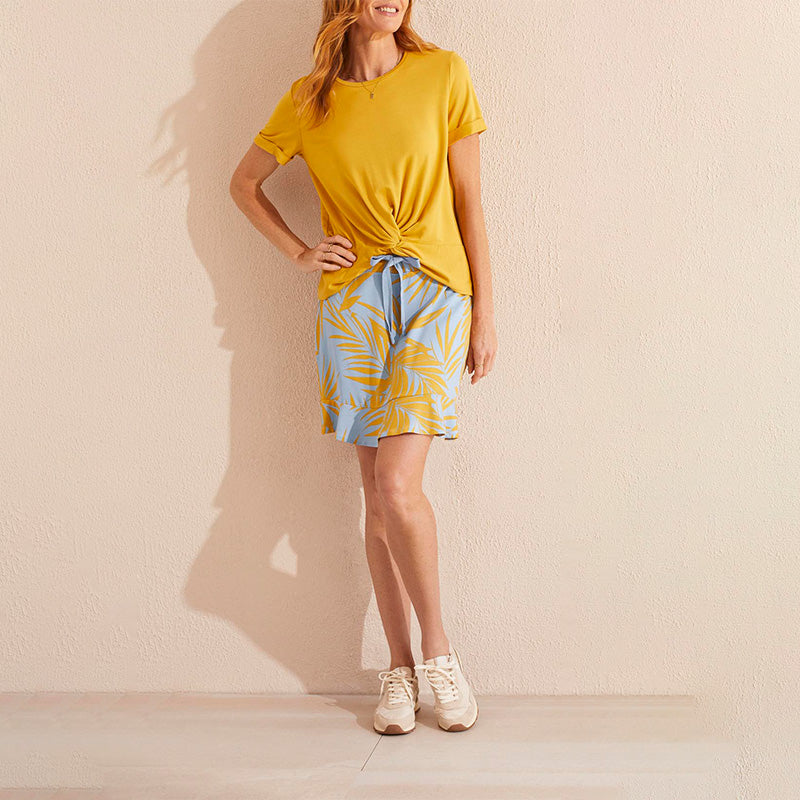 Woman wearing a yellow short sleeve top and a skort with a palm leaf pattern