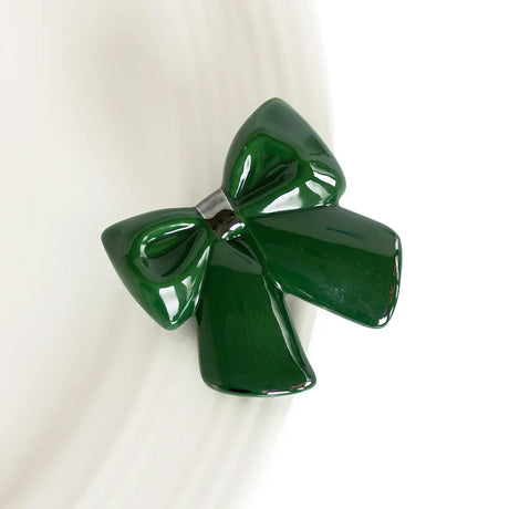 A glossy dark green bow-shaped hair clip or brooch, photographed close-up against a clean white background.