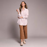 Woman wearing a striped shirt and brown pants against a plain background