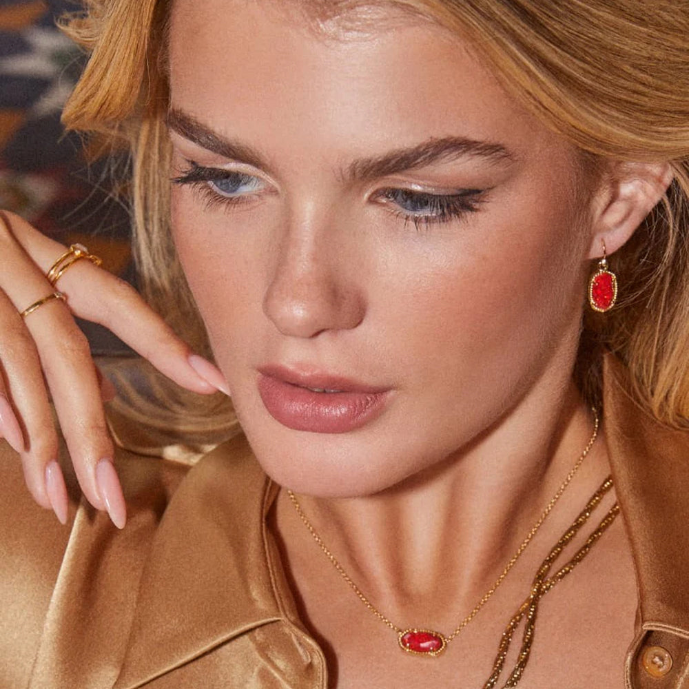 Close-up of a woman wearing gold jewelry with red stones.