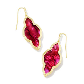 Gold earrings with red shell-like design on a white background