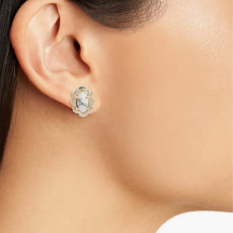 Close-up of an ear wearing a silver earring with a clear gemstone.