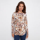Woman wearing a patterned long-sleeve top on a plain background