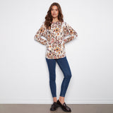 Woman wearing a patterned blouse and blue jeans against a white background
