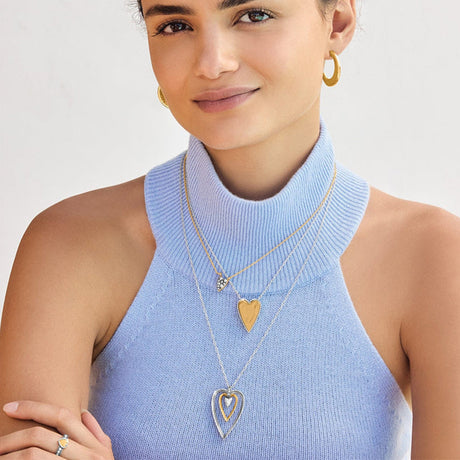 Woman wearing gold necklaces with heart pendants on a white background