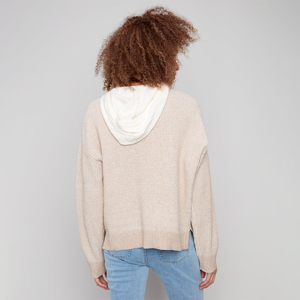 Person wearing a beige sweater with a white hood on a plain background