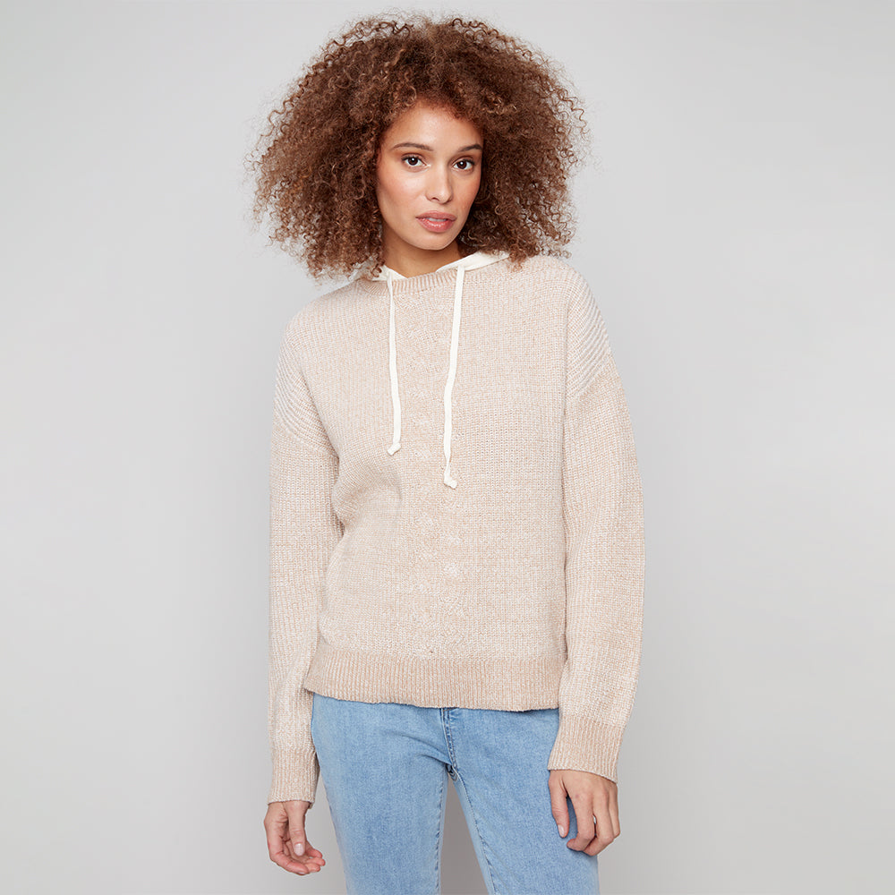 Woman wearing a beige sweater with a white hood against a gray background