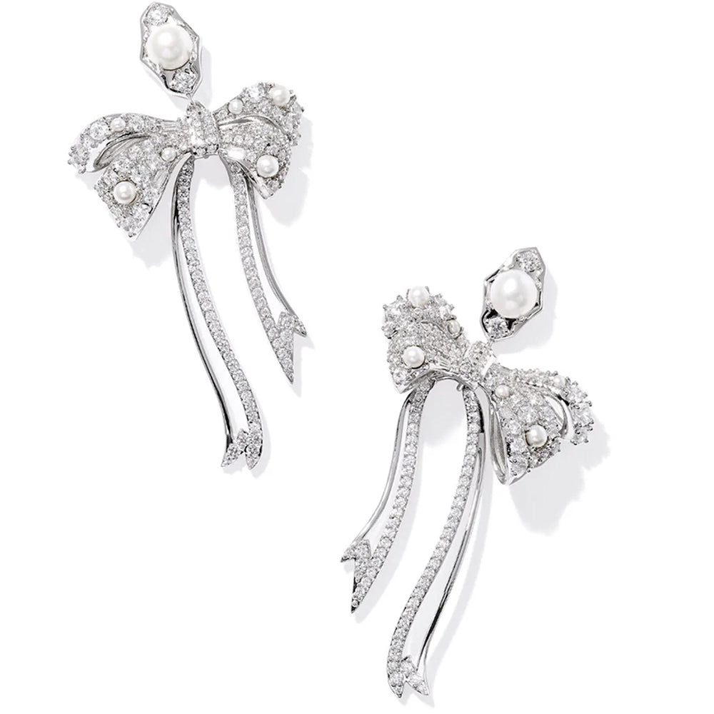 Silver bow-shaped earrings with pearls on a white background
