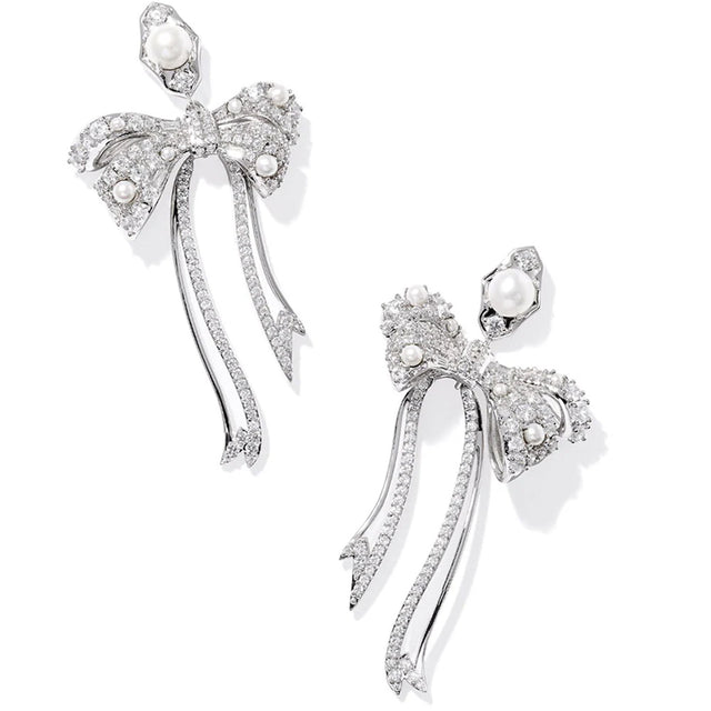 Silver bow-shaped earrings with pearls on a white background