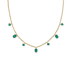 Gold necklace with emerald green gemstones on a white background