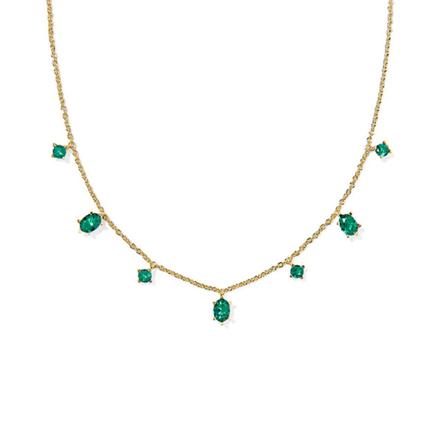 Gold necklace with emerald green gemstones on a white background