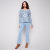 Woman wearing a light blue floral top and jeans on a white background