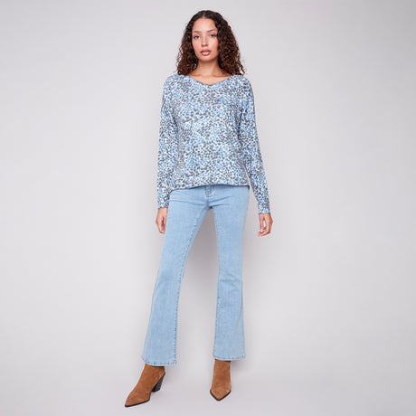 Woman wearing a light blue floral top and jeans on a white background