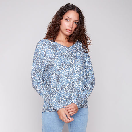 Woman wearing a blue patterned top against a plain background